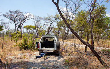 Rundu, Namibia: a man lies under a 4x4 car on a dirt road in the middle of the bush, to see what the problem is. © Roel