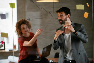 Businesswoman and businessman discussing work in office. Two friends in working together