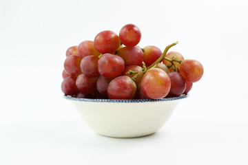 A bowl of red grapes on the vine, isolated on a white background