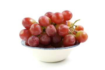 A bowl of red grapes on the vine, isolated on a white background