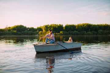Young family go by boat on the river or lake in summertime. Photography for ad or blog about family and travel © Georgii