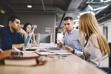 Professional team of architects collaborating on new business project sitting together at desktop in office interior.Male and female colleagues communicating with each other about solving problems