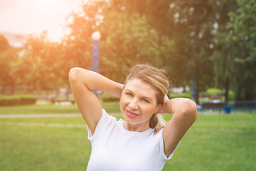 Image of beautiful middle-aged woman laughing in summer park