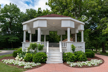 Fototapeta na wymiar Beautiful White Wood Gazebo at Dellwood Park in Lockport Illinois with Green Trees and Flowers during the Summer
