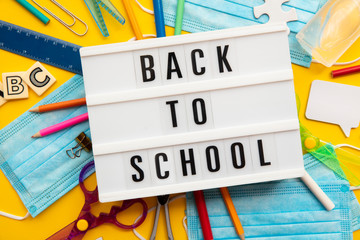 Back to school lightbox message with school equipment and covid masks