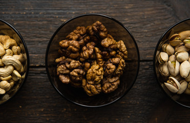 Walnut, pistachio and cashew in a small plates which standing on a black table. Nuts is a healthy vegetarian protein and nutritious food.