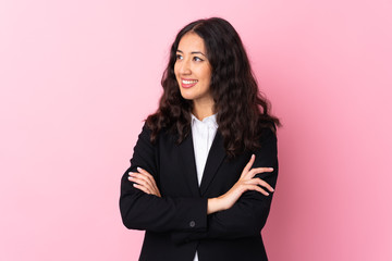 Mixed race business woman over isolated pink background looking to the side