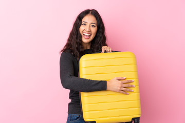 Mixed race woman over isolated pink background in vacation with travel suitcase