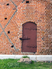 An old red brick castle wall with a metal door, Świecie, Poland