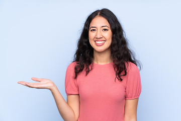 Mixed race woman wearing a sweater over isolated blue background holding copyspace imaginary on the palm