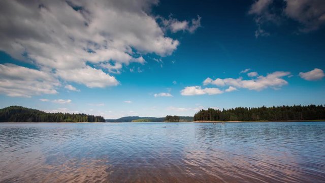 Timelapse with beautiful summer morning view of а mountain lake and moving white fluffy clouds at Shiroka Polyana Dam in the Rhodope Mountains, Bulgaria