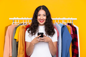 Mixed race woman in a clothing store and talking to mobile