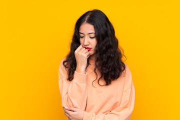 Spanish Chinese woman over isolated yellow background having doubts