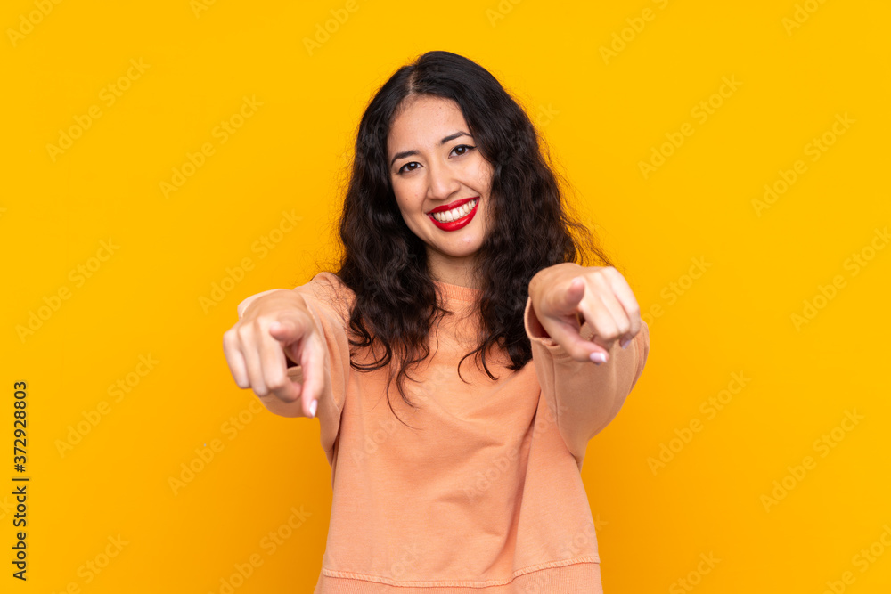 Wall mural Spanish Chinese woman over isolated yellow background points finger at you while smiling