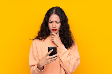 Spanish Chinese woman over isolated yellow background thinking and sending a message