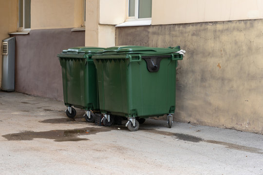 Green plastic garbage containers installed along in the yard of the house. The concept of separate garbage collection