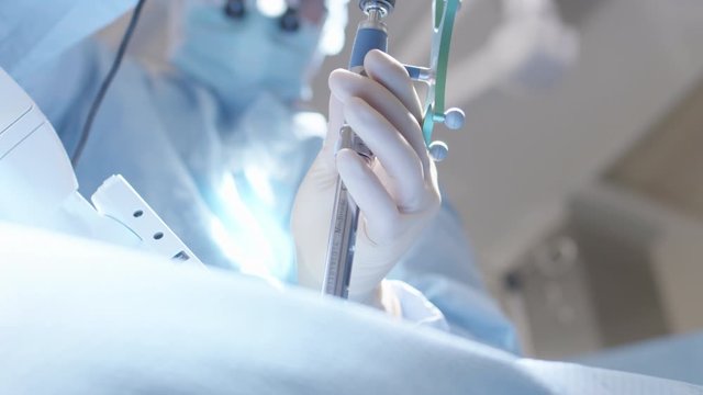 A surgeon rotates medical device during surgery.  