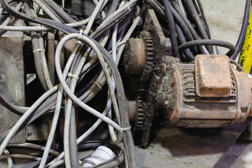 Old motor laid on the floor. The old motor is scrapped. Rusty old motor. Old electric cable