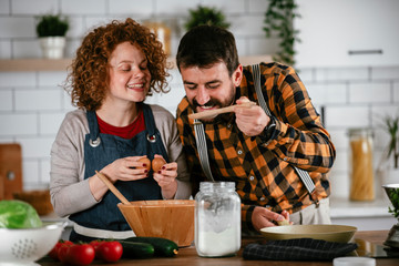 Boyfriend and girlfriend making delicious food at home. Loving couple cooking in kitchen..