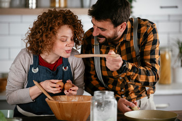 Boyfriend and girlfriend making delicious food at home. Loving couple cooking in kitchen..