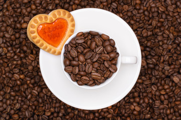 Creative espresso. Coffee beans in white cup and background. Biscuit in a shape of heart 