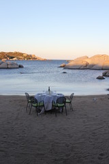 romantic dinner table set on a calm beach at sunset