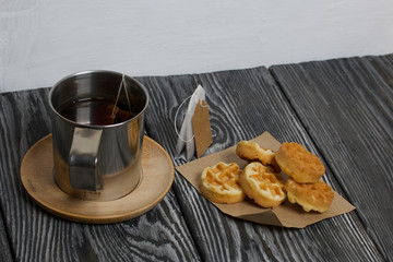Mug of tea and waffles. Nearby is a tea bag. On painted boards. Autumn still life.