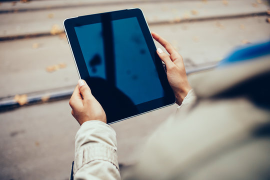 Updating profile on modern touch pad device connected to free 4G internet in hands of young woman.Top cropped view of female person holding digital tablet with black screen outdoors