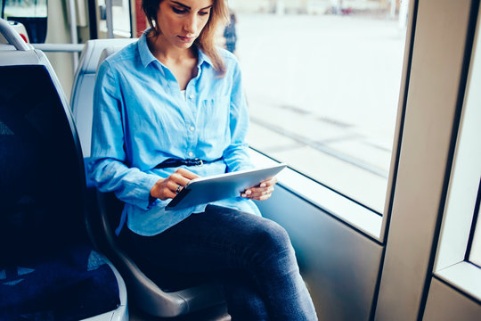 Cropped image of female reading news from portable pc sitting in public transport with free wifi access, hipster girl browse application on modern digital tablet with 4G while sitting in bus .