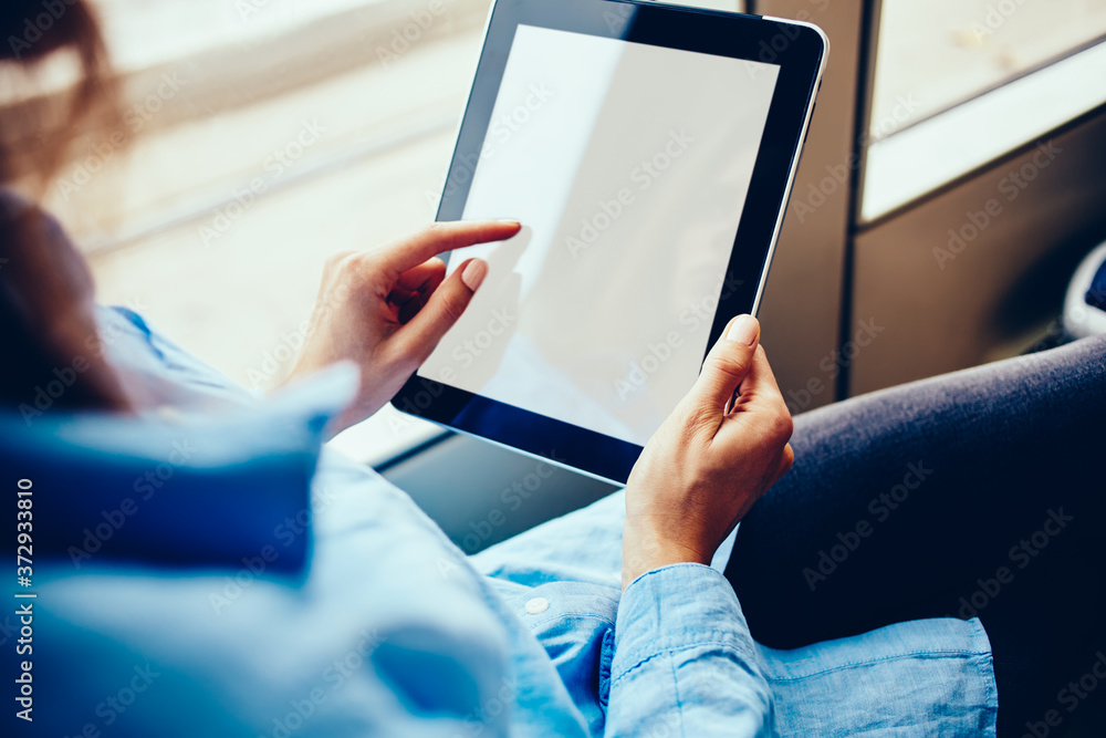 Poster cropped view of woman's hands holding modern touch pad device and touching on blank screen area sitt