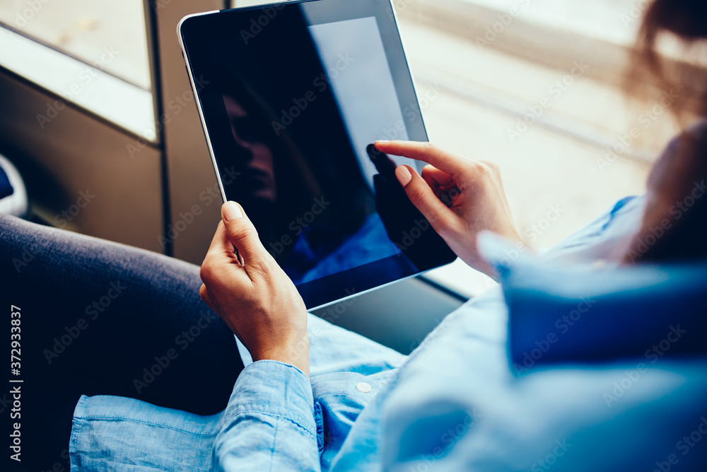 Poster cropped view of hipster girl touching with finger on display of modern touch pad device sitting in t