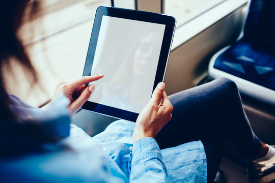 Cropped view of young woman holding modern touch pad device with blank screen area for your internet website content.Hipster girl typing on mock up display of digital tablet updating profile