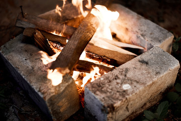 Firewood burns in a fire. Charred sticks. Homemade barbecue made of bricks.