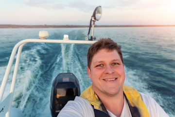 Young adult happy caucasian excited man portrait enjoy having fun driving fast motorboat on pond...