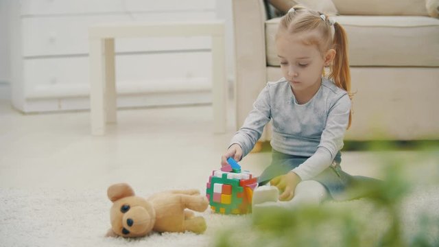 4k slowmotion video of baby playing with colorful pyramid on the carpet.