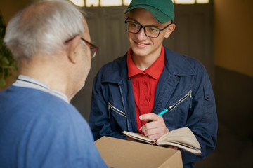 delivery boy gives the package and mail to the elderly