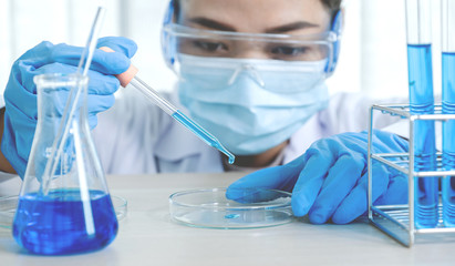 Fototapeta premium Scientists hold the pipette and drop the blue chemical liquid for research and analysis in a laboratory