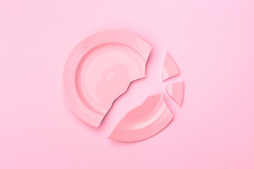broken plate on a light background, pink toning. The concept of breaking up relations