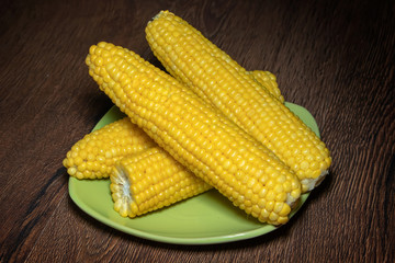 Boiled corn on a plate on wooden background