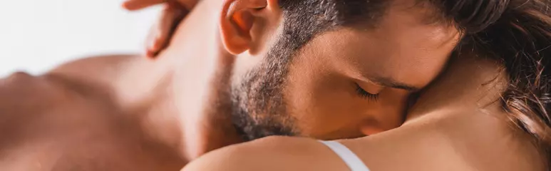Horizontal crop of shirtless man kissing shoulder of girlfriend on grey background © LIGHTFIELD STUDIOS