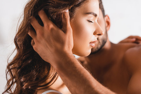 Selective focus of shirtless man touching hair of young woman with closed eye