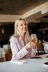 Beautiful businesswoman dressed in the suit drinking wine. Businessman and businesswoman enjoying in the restaurant.