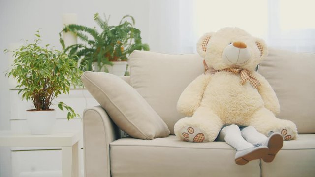 4k video of little blonde girl hiding behind teddy bear and showing silence sign.
