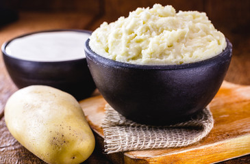 mashed potatoes or cream served in a handmade clay pot, with sour cream in the background on a...