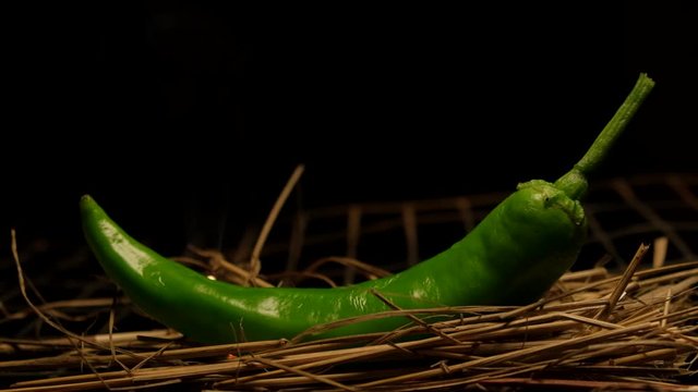 hot chili pepper green in the flame of the fire . slow motion