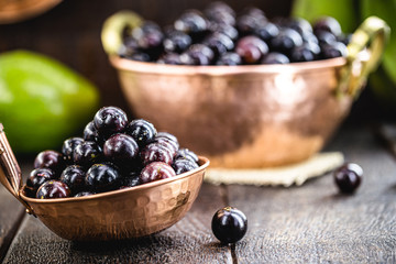 Jaboticaba or jabuticaba, Brazilian and South American fruit, in a copper pot on a rustic table. Fruit for medicinal and culinary use. Spot focus