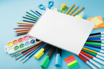 Fototapeta premium An album for drawing and creativity for school with stationery, a palette of colored paints, markers, brushes and pencils.