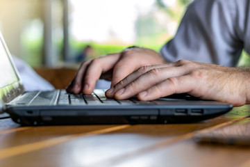 Photo of hands of a businessman on keyboard.Businessman working with laptop on table.Close-up of typing male hands.Businessman using smartphone and laptop computer.Man working on laptop at the office.