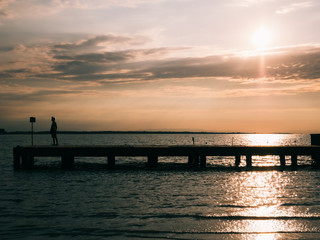 Fototapeta na wymiar an elderly woman watches the sea from a pier