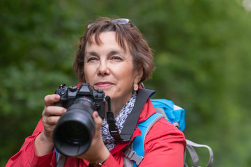 Close-up portrait of a senior birdwatcer woman with camera.